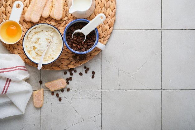 Tiramisu dessert Ingredients for making dessert tiramisu Cooking Italian food dessert Tiramisu with all necessary ingredients cocoa coffee mascarpone cheese on grey stone background Copy space