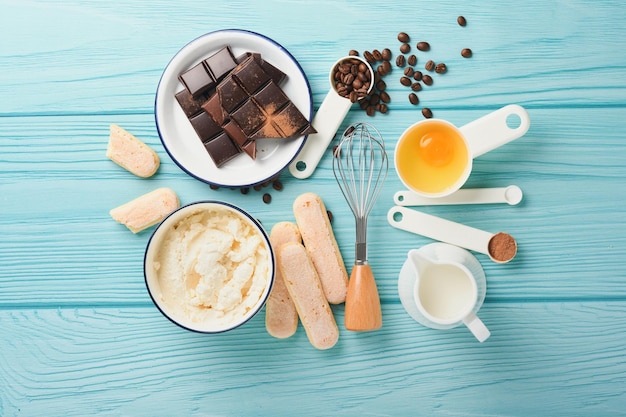 Tiramisu dessert Ingredients for making dessert tiramisu Cooking Italian food dessert Tiramisu with all necessary ingredients cocoa coffee mascarpone cheese on turquoise wooden background Top view