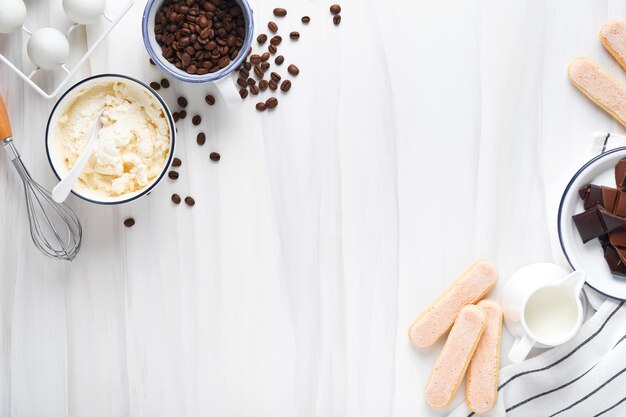 Tiramisu dessert Ingredients for making dessert tiramisu Cooking Italian food dessert Tiramisu with all necessary ingredients cocoa coffee mascarpone cheese on white stone background Mock up