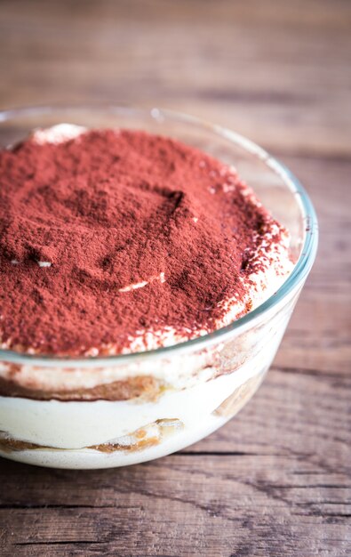 Tiramisu in the glass bowl on the wooden background