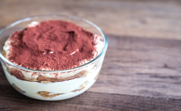 Tiramisù nella ciotola di vetro su legno