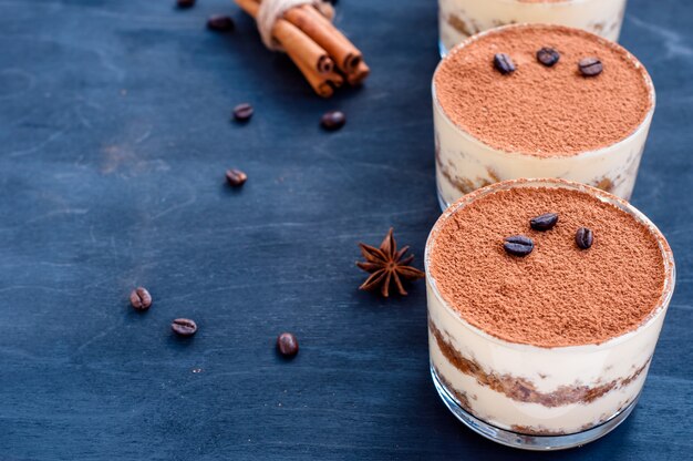 Foto tiramisù in un bicchiere decorato con chicchi di caffè su uno sfondo scuro