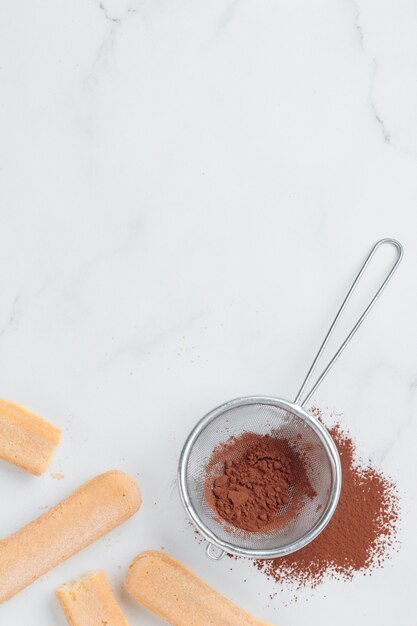 Tiramisu ingrediënten Italiaanse cookie savoiardi en cacaopoeder bovenaanzicht op een witte achtergrond