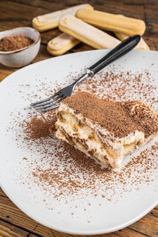 Tiramisù torta italiana con cacao in un piatto. fondo in legno. vista dall'alto.