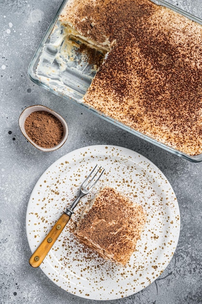 Tiramisù dessert italiano condito con cacao su un piatto. sfondo grigio. vista dall'alto.