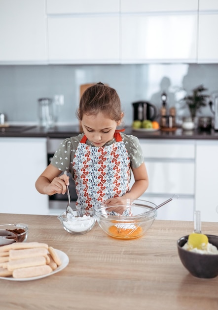 Tiramisu making process in the kitchen little girl making Italian desert with cocoa and espressodipped ladyfingers with mascarpone cream step by step 4