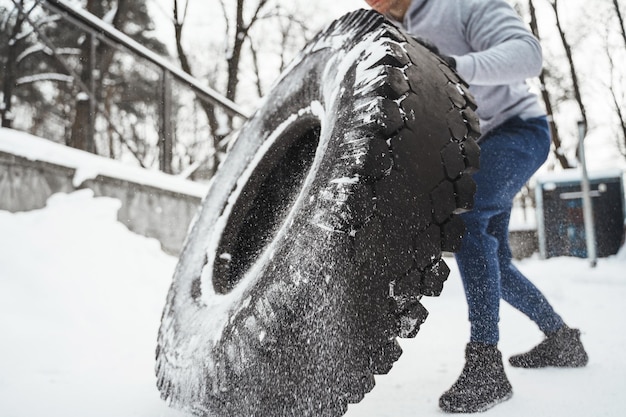 Tire flip oefening Sterke sportman tijdens zijn cross training training tijdens besneeuwde en koude winterdag