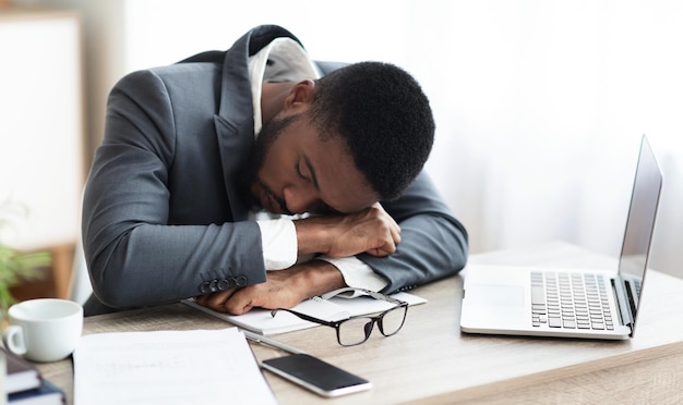 Photo tired african american businessman having a nap at workplace