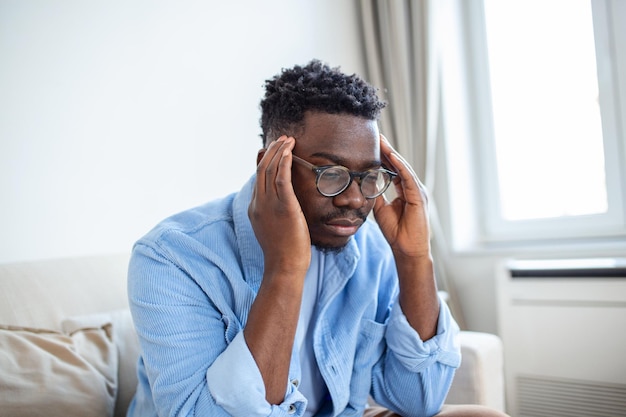 Tired African American man taking off glasses exhausted massaging nose bridge suffering from eye strain after long computer work feeling pain health problem concept