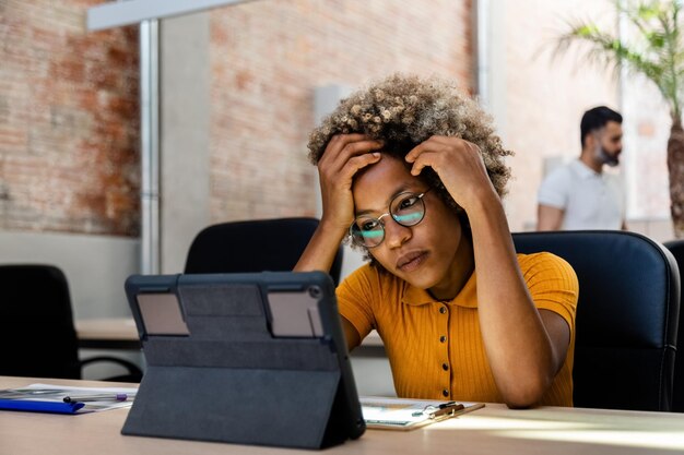 Tired African American young woman working in the office. Forehead rest on hands. Copy space. Business concept.