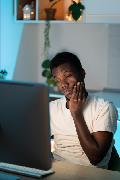 Tired afro male worker or student work on computer overtime need rest and sleep overworked at home