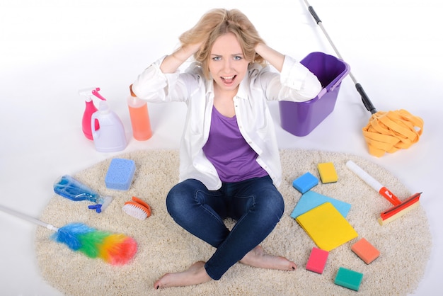 Tired and angry girl scattered cleaning devices.