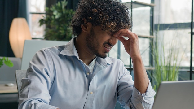 Tired arabian indian man sick businessman feel pain eyestrain ache male employee overworked with