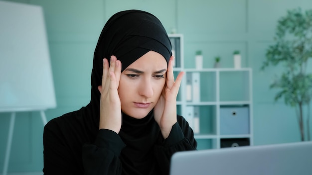 疲れたアラビアのイスラム教徒 黒いヒジャブを着た女性 労働者 学生がオンラインで短い休憩をとります