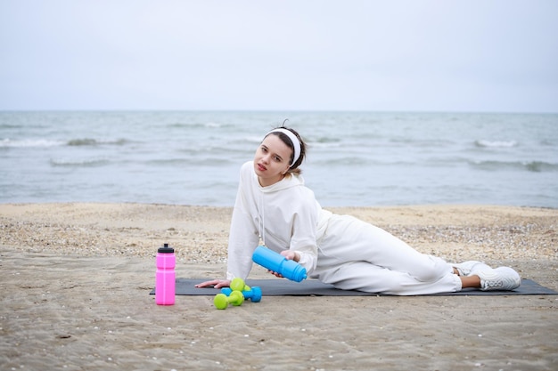 Tired athlete holding water bottle while laying on the mat High quality photo