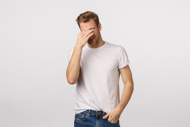 Tired and attractive blond bearded man in white T-shirt