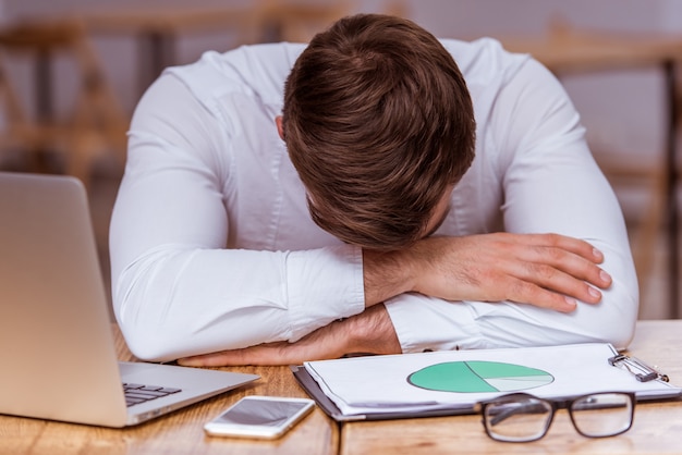 Tired attractive young businessman in white classical shirt.