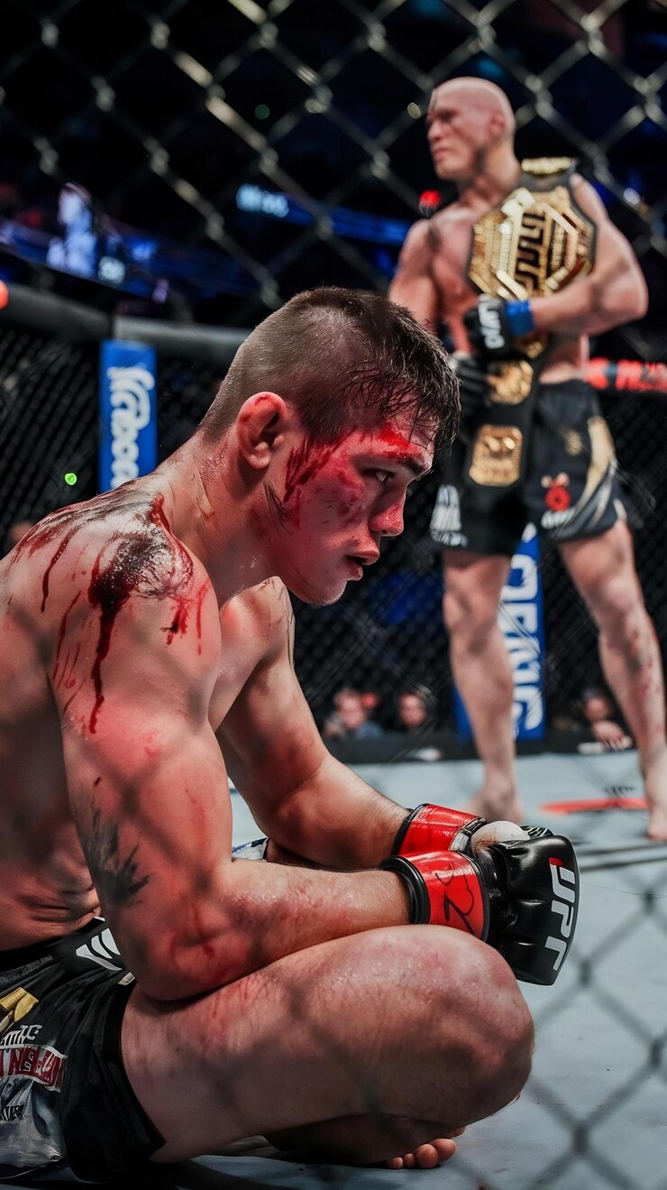 Photo tired and beaten up mixed martial arts fighter resting inside the octagon covered in blood and swe