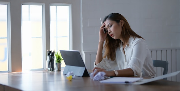 Tired beautiful asian business woman working with headache in office room