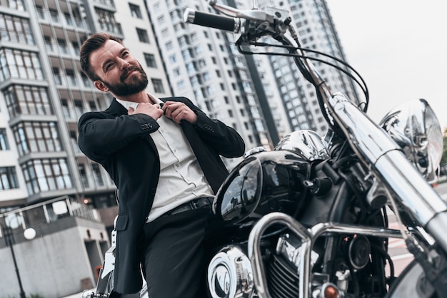 Tired of being serious. Good looking young man in full suit taking off his necktie and smiling 