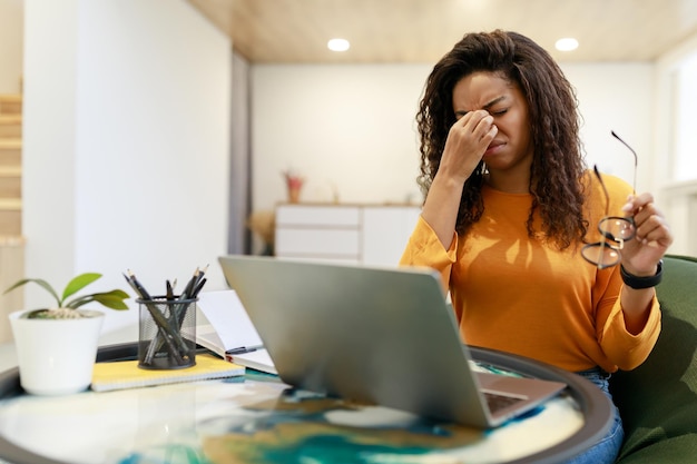 Tired black female worker sitting at desk with pc