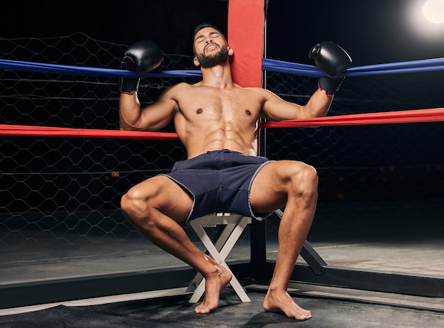 Tired boxer in boxing ring or an arena dark background and spotlight for wrestling mma fighting competition or sports match Strong man with boxing gloves for workout exercise or fitness training