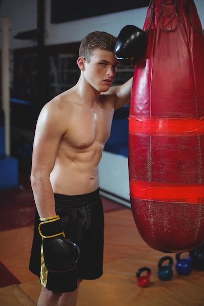 Tired boxer leaning on punching bag