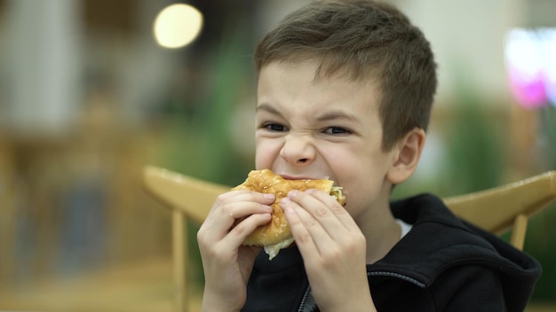 Photo tired boy eating a burger for lunch