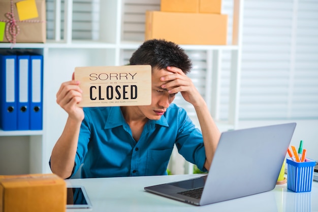 Tired of business man feeling unhappy and stress holding closed sign.