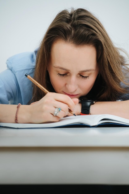 Tired business woman in blue dress shirt fell asleep while writing in a journal