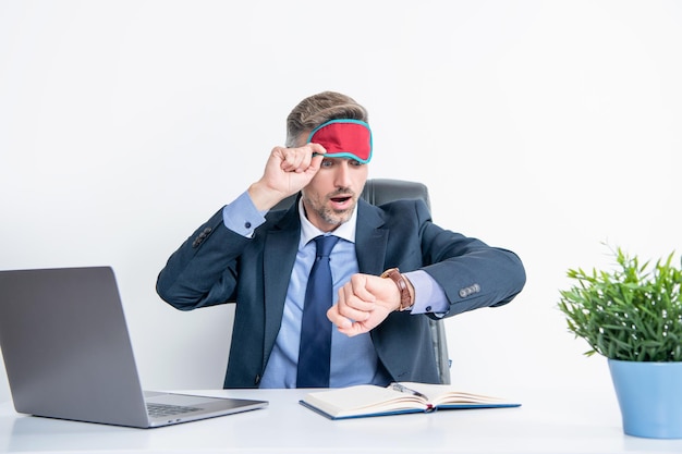 Tired businessman check time in sleep mask at workplace