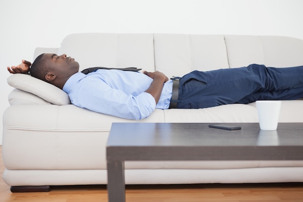 Tired businessman lying on the sofa