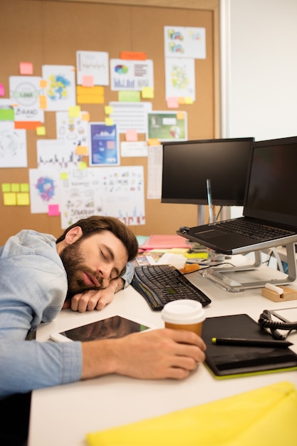 Tired businessman napping in creative office