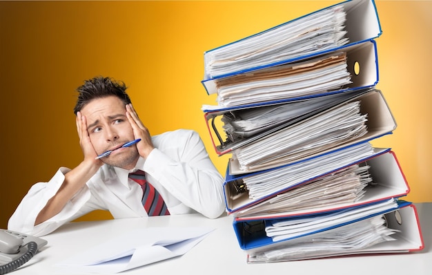 Tired businessman at office with pile of documents