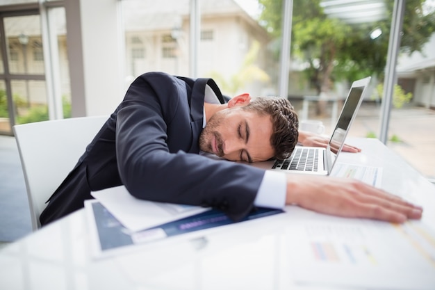Утомленный бизнесмен отдыхая голова на столе