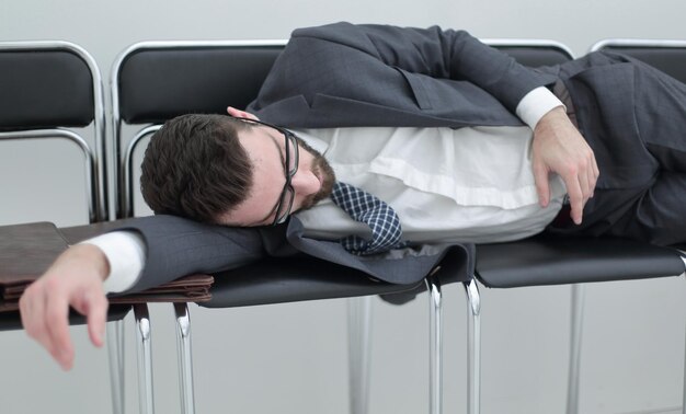 Tired businessman sleeping on chairs in the office hallwaythe\
concept of waiting