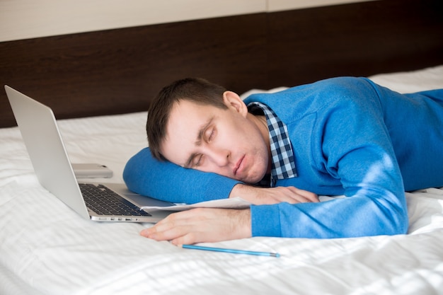Tired businessman sleeping next to his laptop