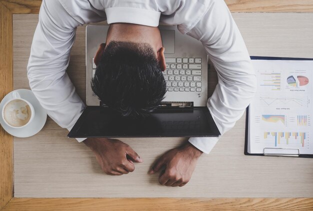 Tired businessman sleeping on laptop over desk in office