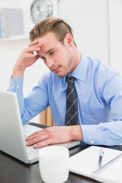 Tired businessman using his laptop