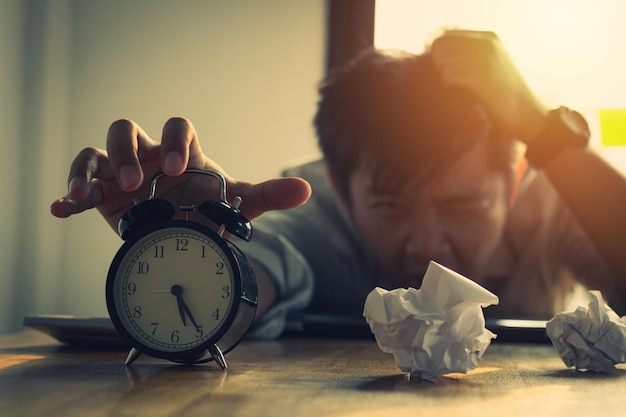 Photo tired businessman with alarm clock on table sitting in office