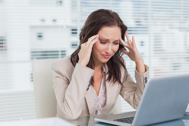 Tired businesswoman having a headache while working on her laptop