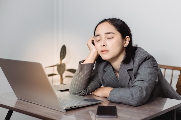 Tired businesswoman sleeping on table in office. Young exhausted girl working from home. Woman using