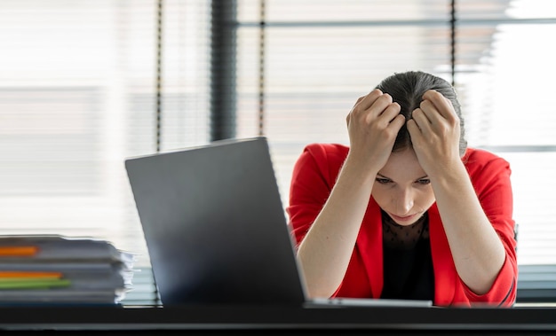 Tired businesswoman with hands on head sitting at desk office