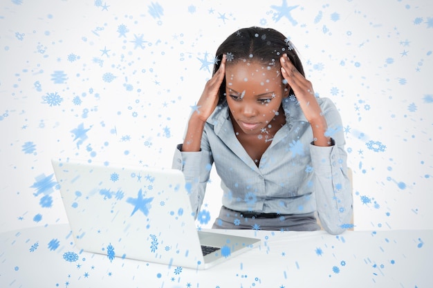 Tired businesswoman working with a laptop against snow falling