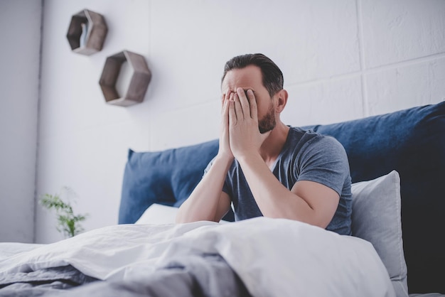 Foto uomo caucasico stanco che cerca di svegliarsi al mattino