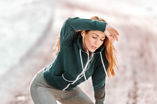 Foto donna sportiva caucasica stanca in abiti sportivi che riposano dalla corsa all'aperto all'inverno.