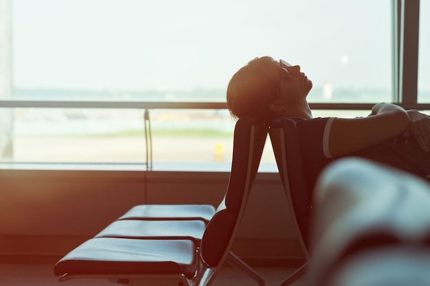 Tired caucasian woman sleeping in airport lounge waiting for flight