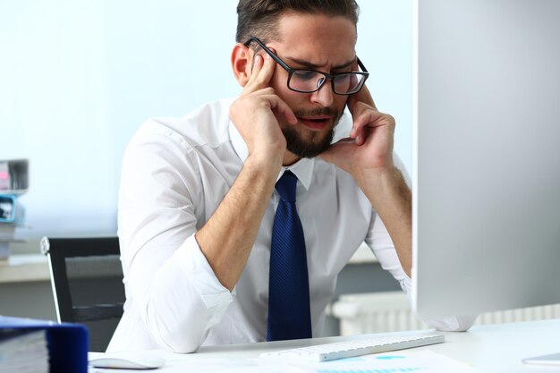 Tired clerk at laptop pc workplace wearing glasses