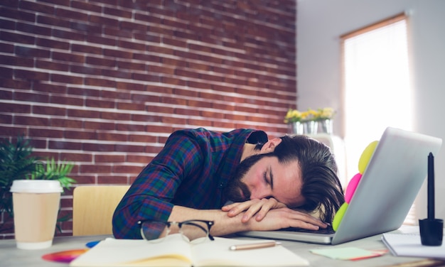 Tired creative editor sleeping on laptop