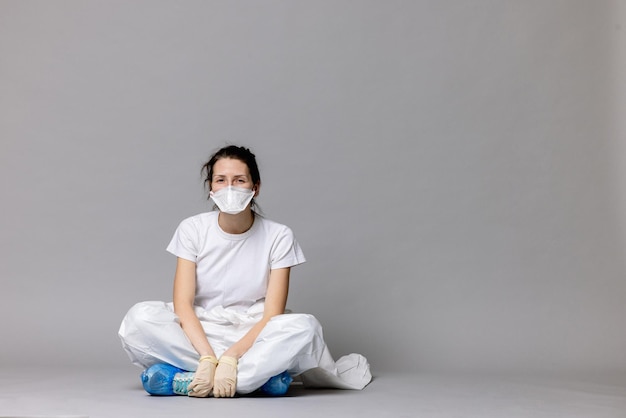 Tired doctor female in a protective suit on the floor exhausted in the fight against a pandemic covid